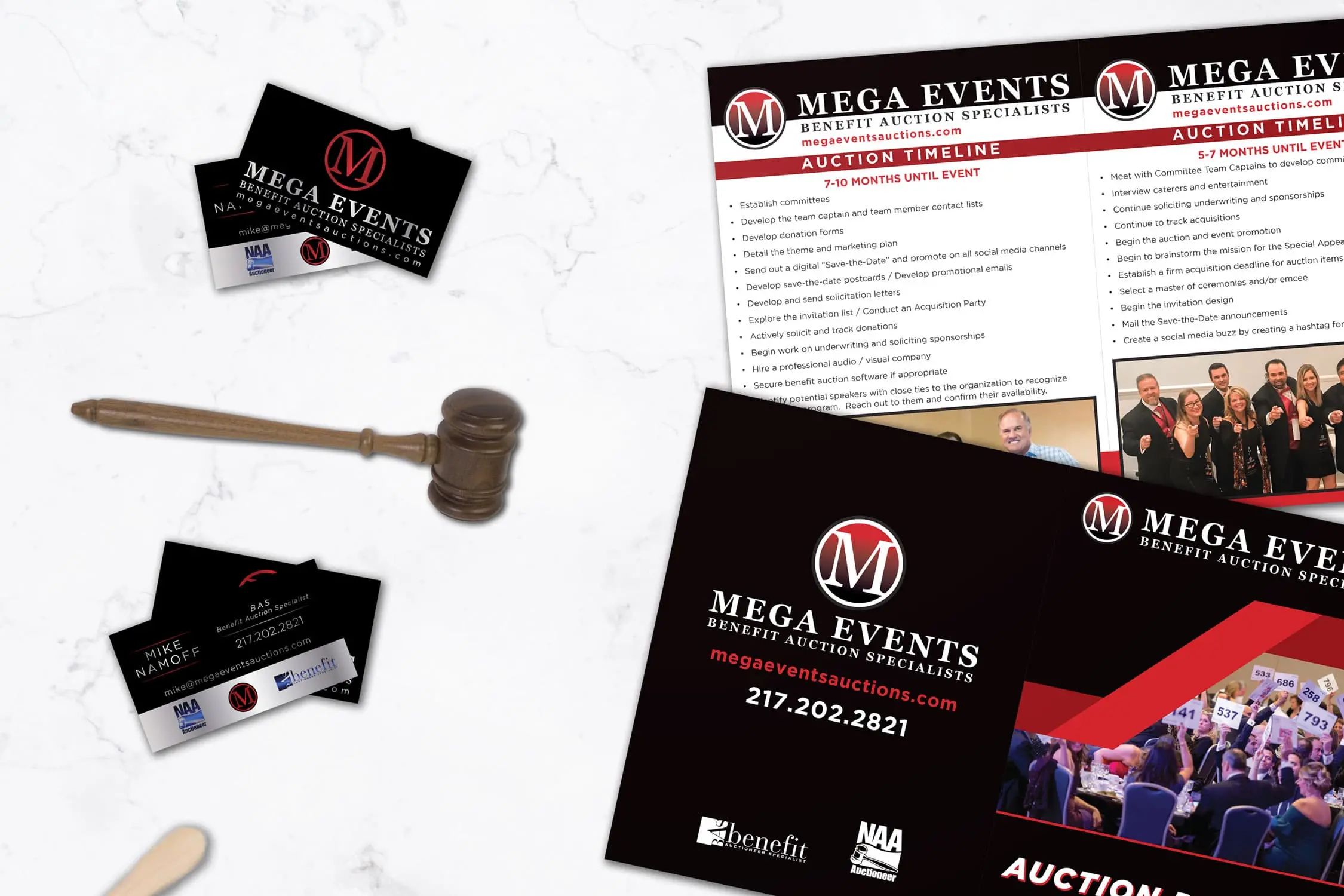 mega events auction timeline booklet and business cards with a gavel and auction paddle on a marble table