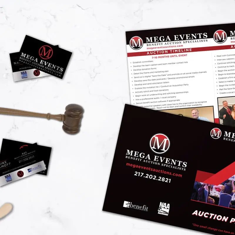 mega events booklet and business cards on a table with gavel and auction paddle